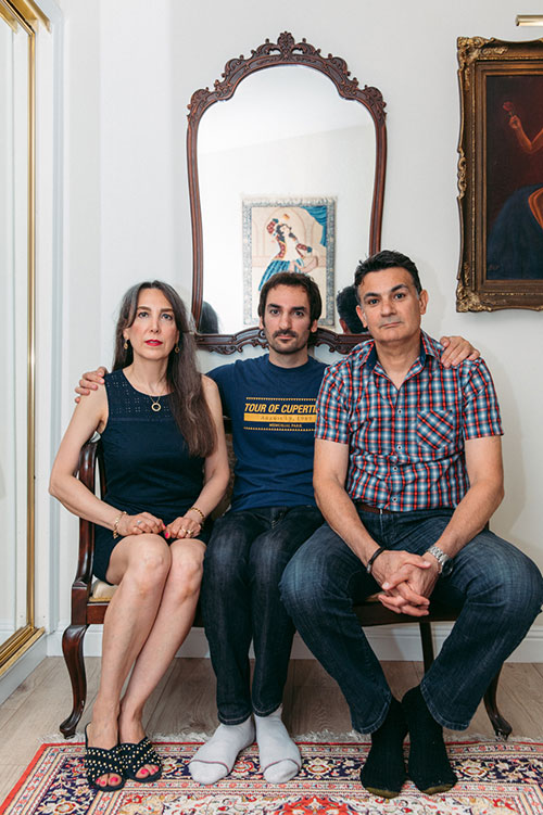 Shervin seated, with his arms around his parents