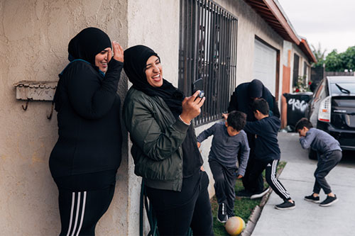 Zahraa laughs with a friend, as her sons play nearby